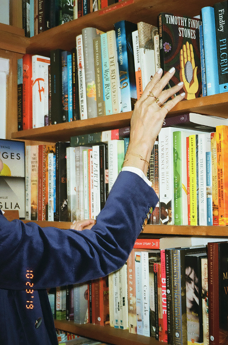 A hand wearing lots of jewelry reaching for a book in a second hand bookstore. Shot on 35mm film.