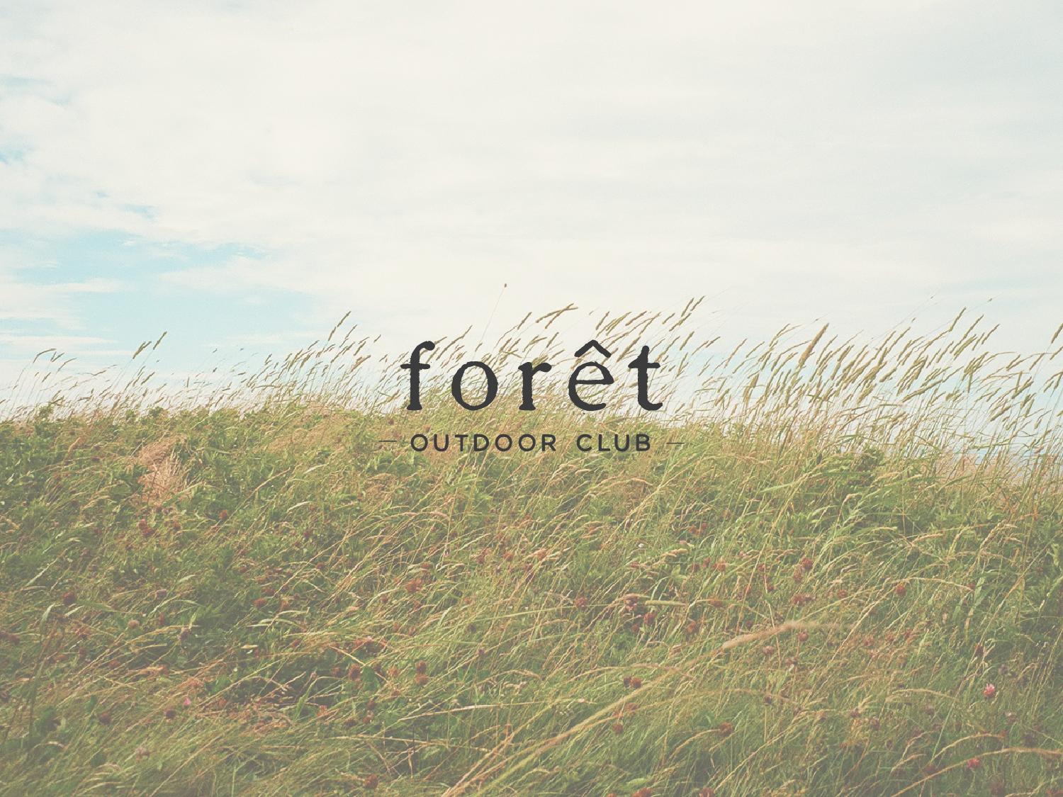 The forêt logo overlaid on a film photo of a grassy field with a blue sky.