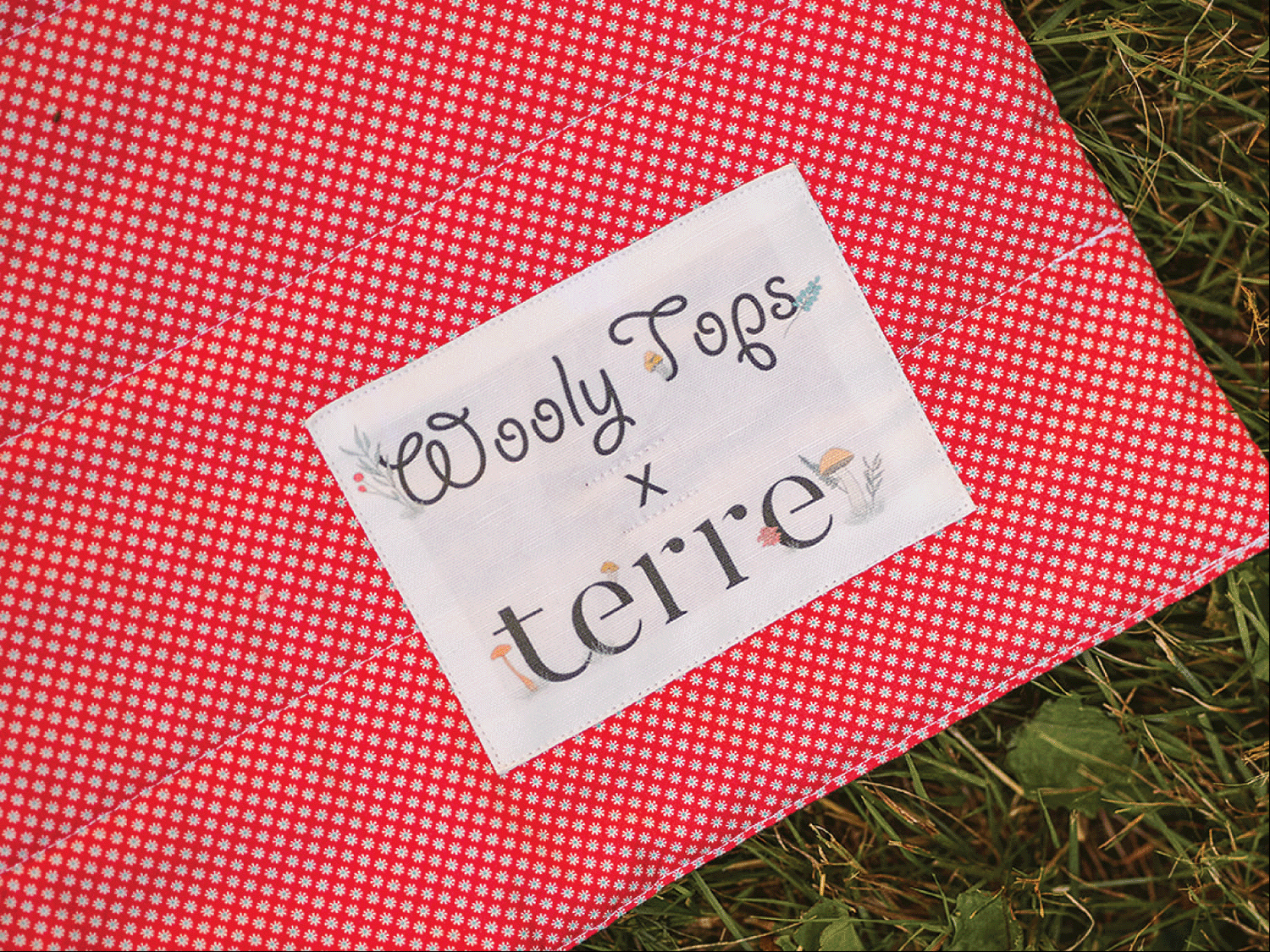A close-up of the Wooly Tops patio blanket in collaboration with Terre. The patch was designed by Aprille.